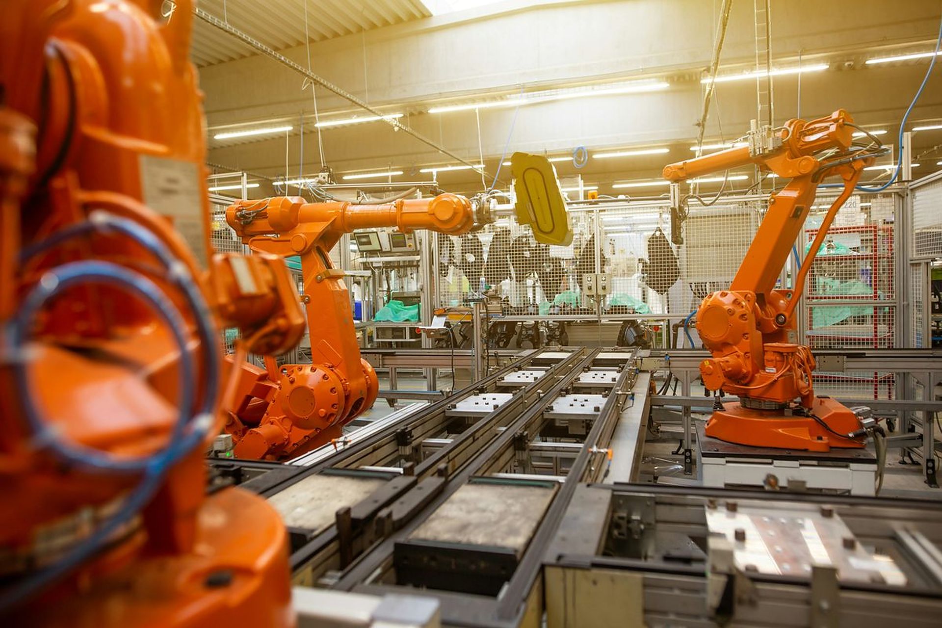 Orange industrial robots along a factory conveyor line