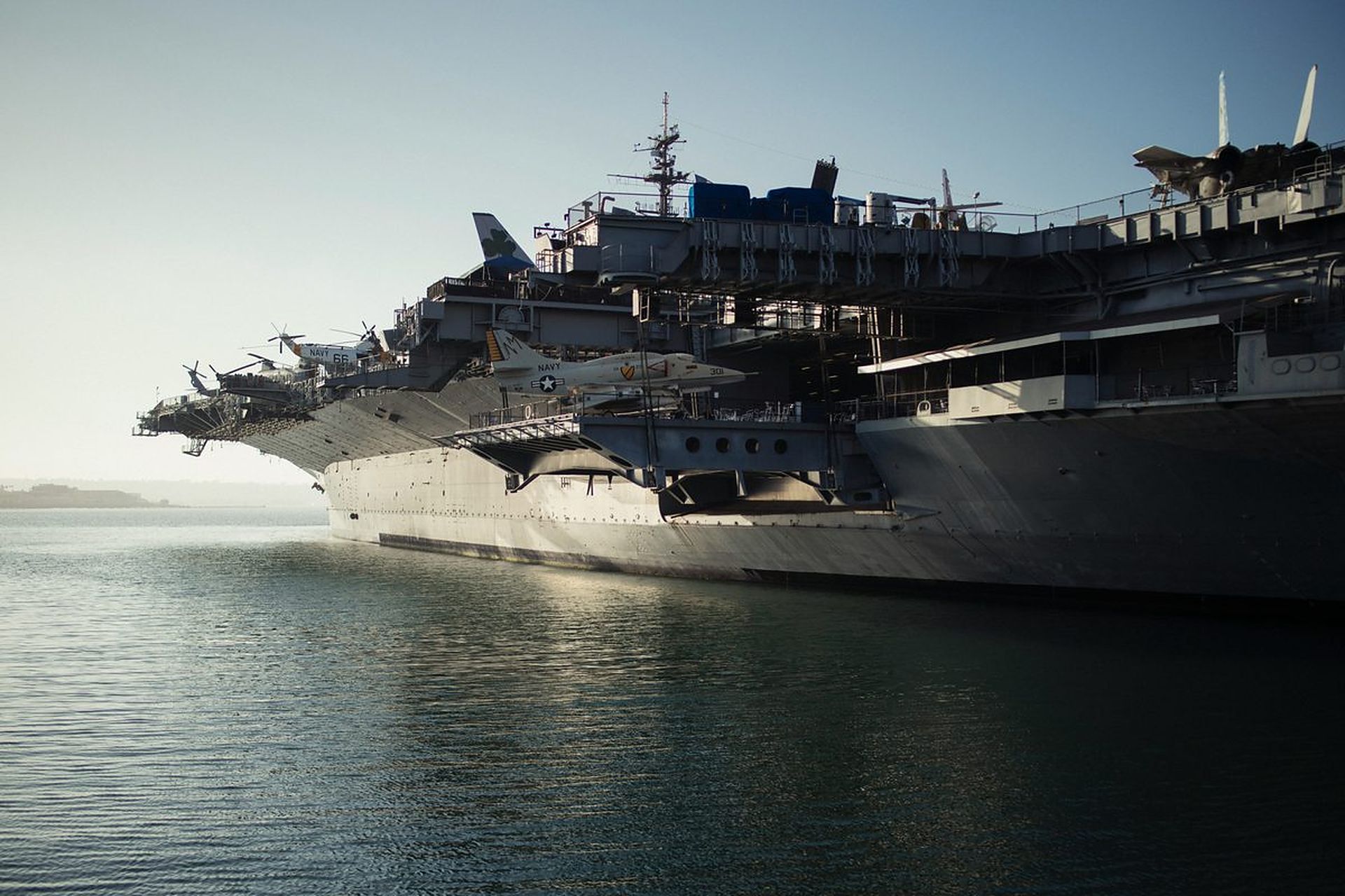 Naval aircraft carrier moored in a harbor at dawn